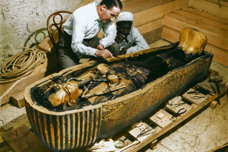 Carter examina o sarcófago do faraó ao lado de um ajudante local