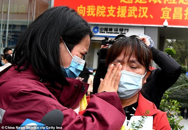 Uma médica é retratada enxugando as lágrimas de sua mãe quando elas se reúnem após dois meses. (China News Service/Divulgação)