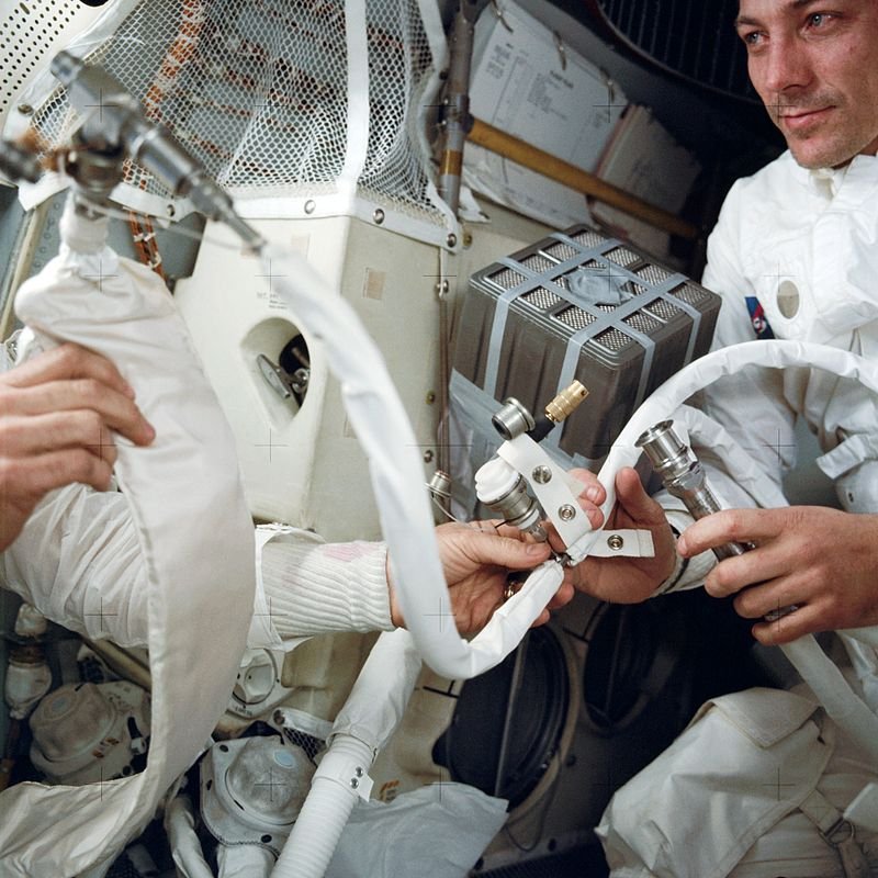 A tripulação da Apollo 13 com o sistema improvisado para circulação de ar, que foi chamado de 