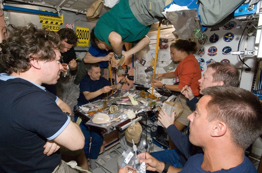 Oito dos 13 tripulantes levados a bordo da ISS pelo ônibus espacial Endeavour se espremem no módulo de refeições.
