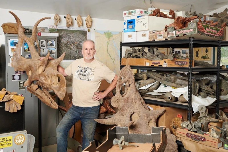 Artista posa ao lado de réplicas de fósseis de dinossauros. (Fonte: PopSci)