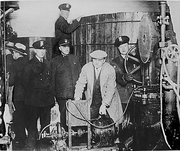 Apreensão de equipamentos para produção de bebida alcollica durante a época da proibição. (Fonte: Wikimedia Commons)